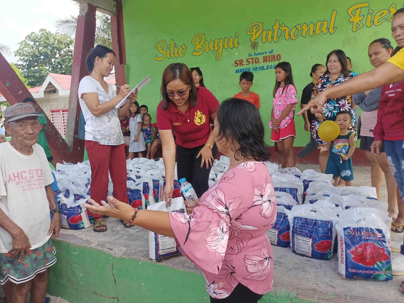 A Jazul team member handing a sack of rice to a resident of Sitio Bugui