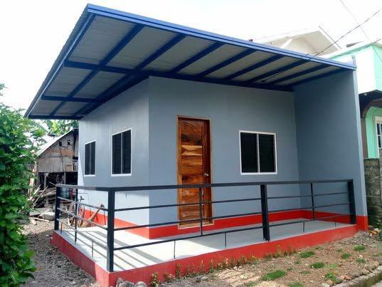 Lola Etang's finished concrete house with a blue roof and porch railing